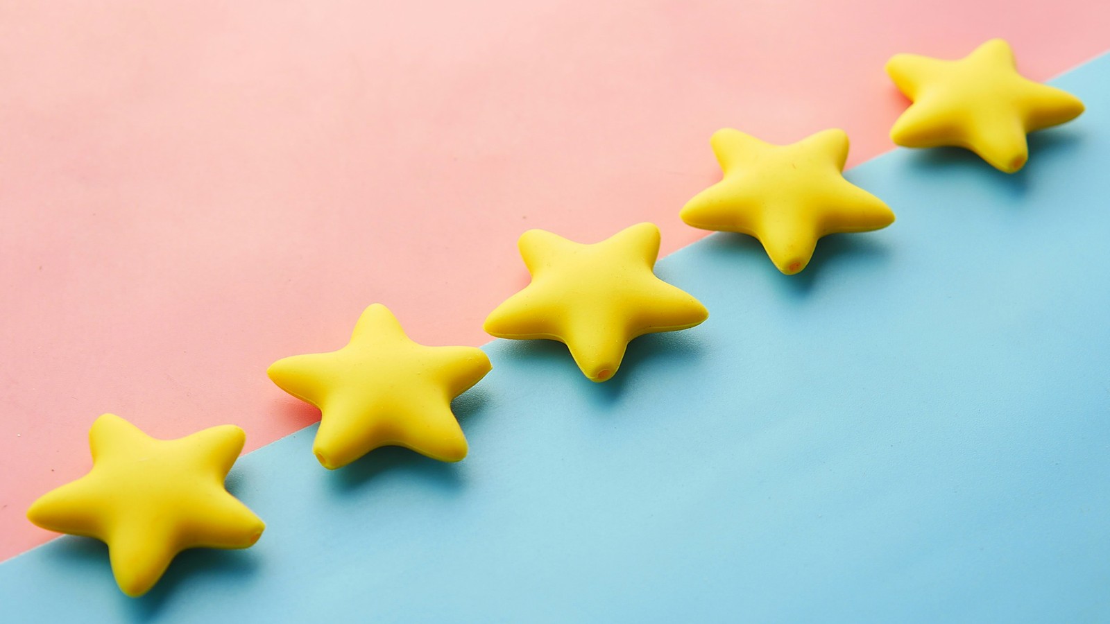 Five yellow star-shaped erasers in a diagonal row across a pink and blue background